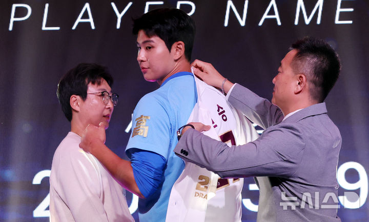[서울=뉴시스] 박영태 기자 = 21일 오후 서울 송파구 롯데호텔 월드 크리스탈볼룸에서 열린 2027 KBO 신인 드래프트, 전체 1순위 지명권을 보유한 키움 허승필 단장이 부산고 좌완투수 하현승을 지명한 후 유니폼을 입혀주고 있다. 2026.09.21. since1999@newsis.com