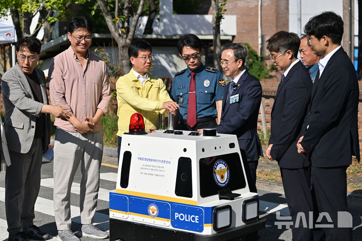 [전남광주=뉴시스] 이영주 기자 = 박병규(왼쪽 세번째) 전남광주 광산구청장과 김만수(가운데) 광산경찰서장, 임문영(오른쪽 세번째) 국회의원이 21일 오후 전남광주 광산구 남부대학교 수영장 주차장에서 열린 광주 광산경찰서의 AI 순찰 로봇 현장 시연에 참여하고 있다. 순찰 로봇은 무게 120㎏의 사륜형으로 4방향 라이다와 초음파 기반 센서를 탑재해 화재와 쓰러진 사람을 감지할 수 있다. 로봇이 감지한 사고는 제조사 관제실로 신고된 뒤 소방·경찰로 이첩된다. 2026.09.21.leeyj2578@newsis.com