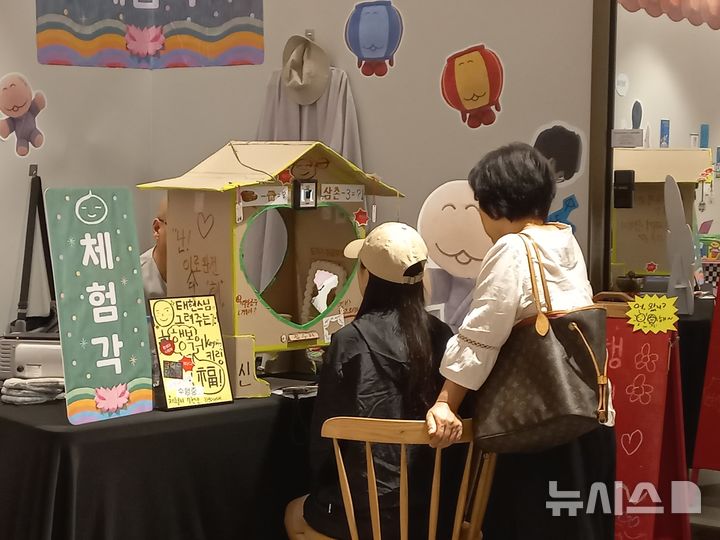 [서울=뉴시스] 박지우·이수진 인턴기자 = 17일 '행복사-마음이 살찌는 절' 불교 팝업에서 태현스님께 '마음 캐리커쳐' 체험을 받는 방문객의 모습. 2026.09.17