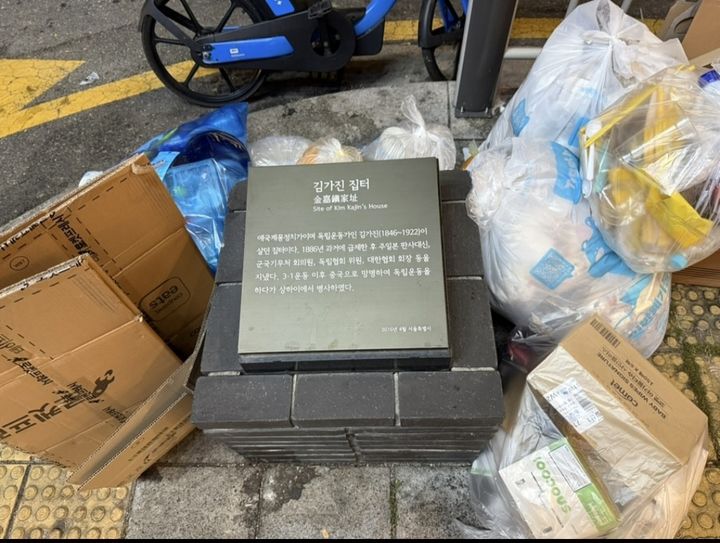 [서울=뉴시스] 서울 종로구 서촌에 있는 동농 김가진 집터 표지석 주변에 쓰레기봉투 등이 놓여 있다. (사진출처: 스레드 캡처)2026.09.22.