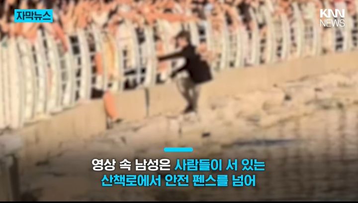 [서울=뉴시스] 부산 북항친수공원에서 한 남성이 안전 펜스를 넘어 수로 가까이 내려가는 모습이 포착돼 화제가 되고 있다. (사진='KNN NEWS' 캡처)