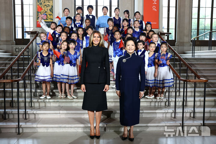 [워싱턴DC=AP/뉴시스]24일 워싱턴 스미소니언 국립아시아미술관에서 중국의 펑리위안 영부인(오른쪽)과 멜라니아 트럼프 영부인이 호프 중국학교 합창단 학생들과 함께 기념 촬영을 하고 있다.2026.09.24.