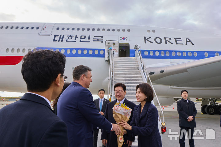 [앵커리지=뉴시스] 김진아 기자 = 이재명 대통령과 김혜경 여사가 26일 오후(현지 시간) 순방 귀국길 경유지인 미국 앵커리지 테드 스티븐스 국제공항에서 영접나온 인사에게 꽃다발을 받고 있다. (공동취재) 2026.09.27. bluesoda@newsis.com