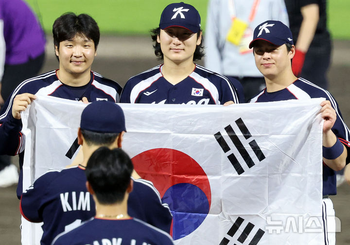 [도요하시(일본)=뉴시스] 이영환 기자 = 27일 오후(현지 시간) 일본 아이치현 도요하시 시민구장에서 열린 2026 아이치·나고야 아시안게임 야구 결승전 한국과 일본의 경기, 3-1로 승리하며 금메달을 획득한 한국 문보경, 곽빈, 노시환이 태극기를 들고 기념촬영을 하고 있다. 2026.09.27. 20hwan@newsis.com