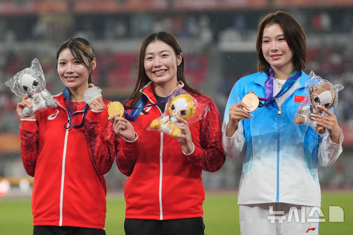 [나고야=신화통신/뉴시스] 28일 일본 나고야에서 열린 2026 아이치·나고야 아시안게임 여자 100m 허들 결승에서 금메달을 차지한 일본의 후쿠베 마코(가운데)가 은메달리스트 나카지마 히토미(왼쪽), 동메달리스트 중국의 우옌니와 함께 시상대에 올라 기념촬영을 하고 있다.2026.0928.