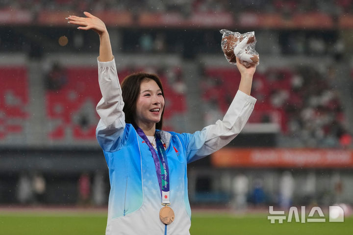[나고야=신화통신/뉴시스] 28일 일본 나고야에서 2026 아이치·나고야 아시안게임 여자 100m 허들 결승에서 중국의 우옌니가 동메달을 차지한 뒤 시상대에서 손을 흔들고 있다.2026.0928