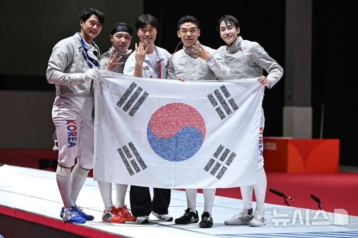 [서울=뉴시스] 윤현성 기자 = 2026 아이치·나고야 아시안게임 펜싱 남자 사브르 단체전에서 4연패를 달성한 대한민국 대표팀 선수단이 국민 응원 메시지가 담긴 태극기를 들고 기념 촬영을 하고 있다. (사진=SK텔레콤 제공) hsyhs@newsis.com