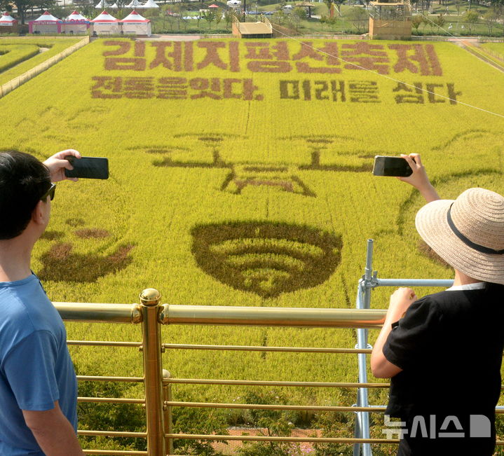 [김제=뉴시스] 김얼 기자 = 제28회 김제지평선축제 개막을 이틀 앞둔 29일 전북 김제시 벽골제에 마련된 들녁마당을 찾은 시민들이 유색벼로 조성한 대지아트를 감상하고 있다. 2026.09.29. pmkeul@newsis.com