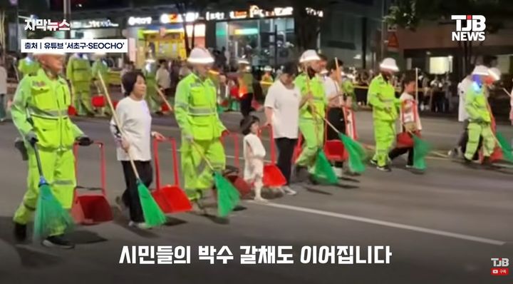 [서울=뉴시스] 서리풀뮤직페스티벌 마지막 날 환경공무관과 주민들이 청소도구와 살수차 등을 동원해 '서리풀 청소 퍼레이드'를 진행하고 있다. (사진='TJB NEWS' 캡처)