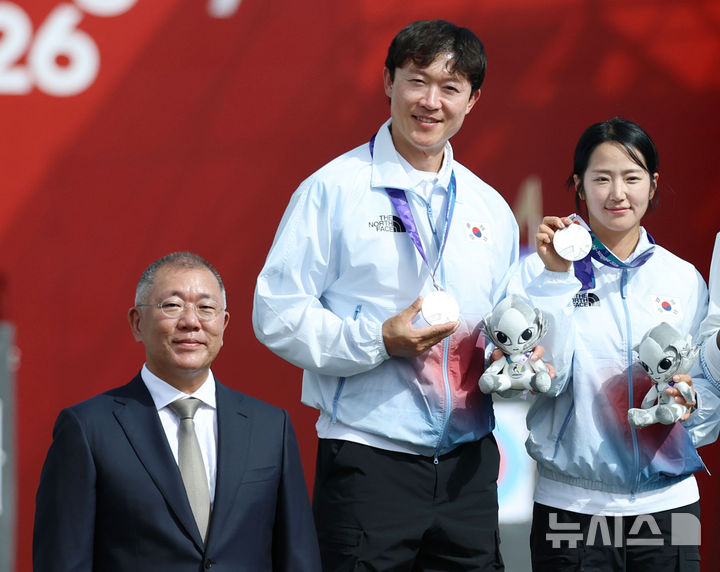 [오카자키(일본)=뉴시스] 김금보 기자 = 30일(현지 시간) 일본 아이치현 오카자키시 오카자키 중앙종합공원 내 다목적 광장에서 열린 2026 아이치·나고야 아시안게임 양궁 컴파운드 혼성 단체에서 은메달을 차지한 박정윤과 최용희가 대한양궁협회 회장인 정의선 현대자동차그룹 회장과 기념촬영을 하고 있다. 2026.09.30. kgb@newsis.com