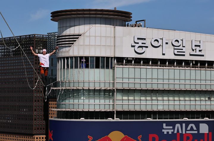 [서울=뉴시스] 전신 기자 = 1일 오후 에스토니아 출신 레드불 슬랙라인 선수 얀 루스가 서울 광화문 사거리 약 120m 상공에서 '레드불 서울 줄타기' 퍼포먼스를 선보이고 있다.슬랙라인은 두 지점 사이를 이어 팽팽하게 설치한 폭 2.5~5cm 안팎의 줄 위에서 균형을 잡아 걷거나 점프, 회전 등의 기술을 선보이는 스포츠로, 이날 얀 루스는 코리아나호텔을 출발해 동아미디어센터를 반환점으로 돌아오는 편도 160m 구간의 고공 왕복 횡단에 도전했다. (공동취재) 2026.10.01. photo@newsis.com