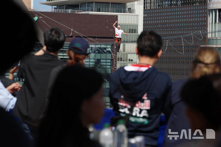 [서울=뉴시스] 전신 기자 = 슬랙라인 선수 얀 루스가 1일 서울 광화문에서 열린 ‘레드불 서울 줄타기’ 행사에서 고공 외줄타기를 하고 있다.슬랙라인은 두 지점 사이를 이어 팽팽하게 설치한 폭 2.5~5cm 안팎의 줄 위에서 균형을 잡아 걷거나 점프, 회전 등의 기술을 선보이는 스포츠다. (공동취재) 2026.10.01. photo@newsis.com