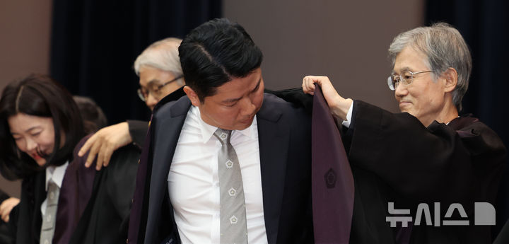 [서울=뉴시스] 박주성 기자 = 조희대 대법원장이 2일 오후 서울 대법원 대강당에서 열린 신임 법관 임명식에 참석해 신임법관에게 법복을 입혀주고 있다. 2026.10.02. park7691@newsis.com