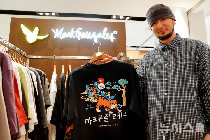 [전남광주=뉴시스]광주신세계 플레이스팟 마크곤잘레스 매장에서 직원이 코리아 에디션 티셔츠를 들고 포즈를 취하고 있다.(사진=광주신세계 제공)