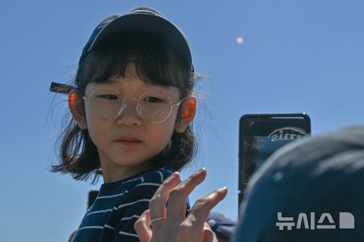 [전남광주=뉴시스] 이영주 기자 = 누리호 5차 발사가 진행된 7일 오후 전남광주 고흥군 우주발사전망대에서 한 어머니가 하늘로 날아오른 누리호를 배경으로 딸을 촬영해주고 있다. 2026.10.07. leeyj2578@newsis.com