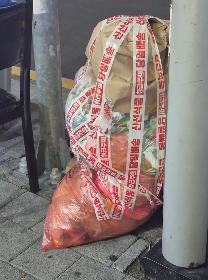 [서울=뉴시스] 최근 경남 거제시의 한 음식점 앞에서 규격 종량제봉투 위에 투명 비닐봉투와 종이봉투가 층층이 쌓여 혼합 배출된 모습이 포착됐다. (사진=스레드 캡쳐) 2026.10.08.