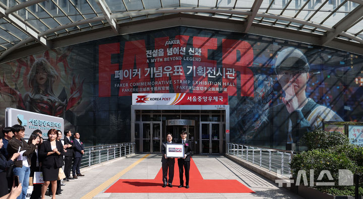 [서울=뉴시스] 김선웅 기자 = e스포츠 리그 오브 레전드 '페이커' 이상혁 선수가 10일 서울 중구 서울중앙우체국 우표박물관에서 열린 페이커 기념우표 기획전시관 개관식에서 박인환 우정사업본부장으로부터 오는 23일 발매하는 페이커 기념우표를 기념선물로 전달받고 있다. 2026.10.10. mangusta@newsis.com