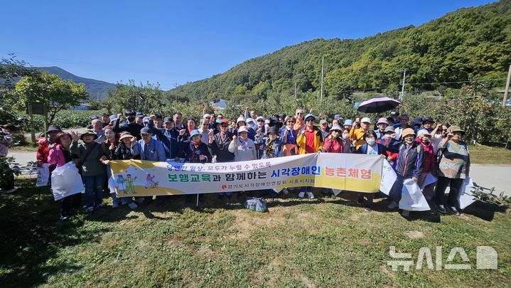 [시흥=뉴시스] 최근 충북 충주 새봄농원에서 관내 시각장애인 90명을 대상으로 진행된 '보행 교육 및 사과 따기 농촌 체험 프로그램' 참석자들이 기념촬영을 하고 있다. (사진=시흥시 제공). 2026.10.11. photo@newsis.com 