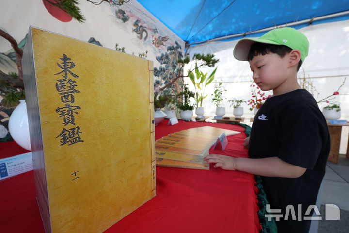 [서울=뉴시스] 김명년 기자 = 11일 오전 서울 강서구 서울식물원 진입광장 일원에서 열린 2026 허준축제에서 한 아이가 동의보감 모형을 살펴보고 있다. kmn@newsis.com