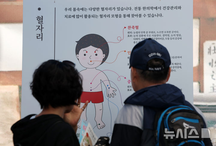 [서울=뉴시스] 김명년 기자 = 11일 오전 서울 강서구 서울식물원 진입광장 일원에서 열린 2026 허준축제에서 관람객이 혈자리 안내문을 살펴보고 있다. kmn@newsis.com
