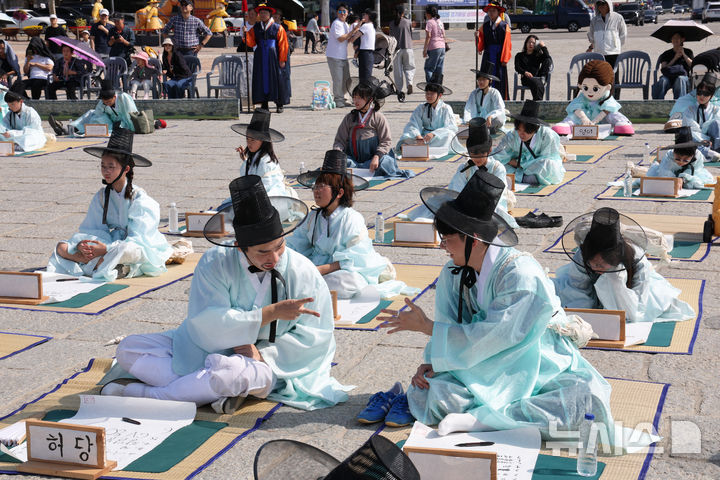 [수원=뉴시스] 김종택 기자 = 제63회 수원화성문화제가 열린 11일 경기도 수원시 화성행궁 광장에서 종이상자를 쌓아 화홍문을 실제 크기의 70%로 만든 '시민의 위대한 건축 화홍' 앞에서 조선시대 과거시험을 재현한 '별시'가 진행되고 있다. 2026.10.11. jtk@newsis.com