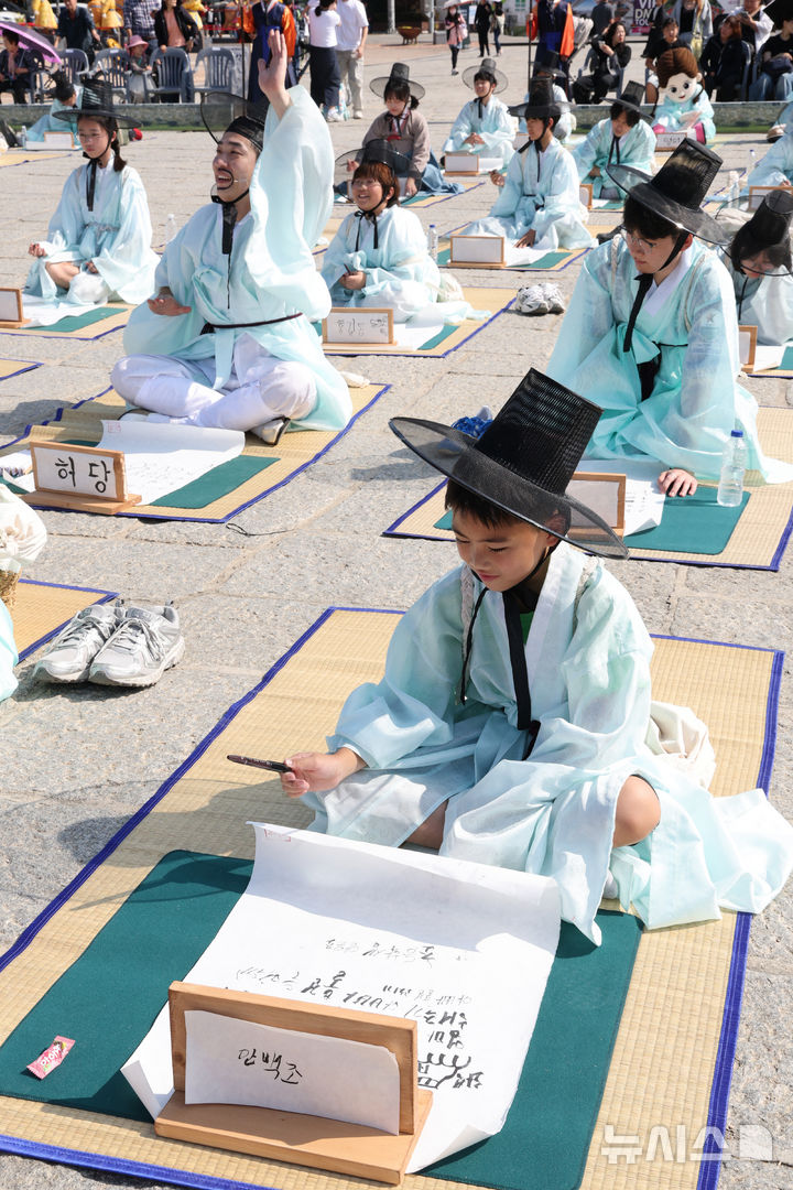 [수원=뉴시스] 김종택 기자 = 제63회 수원화성문화제가 열린 11일 경기도 수원시 화성행궁 광장에서 종이상자를 쌓아 화홍문을 실제 크기의 70%로 만든 '시민의 위대한 건축 화홍' 앞에서 조선시대 과거시험을 재현한 '별시'가 진행되고 있다. 2026.10.11. jtk@newsis.com