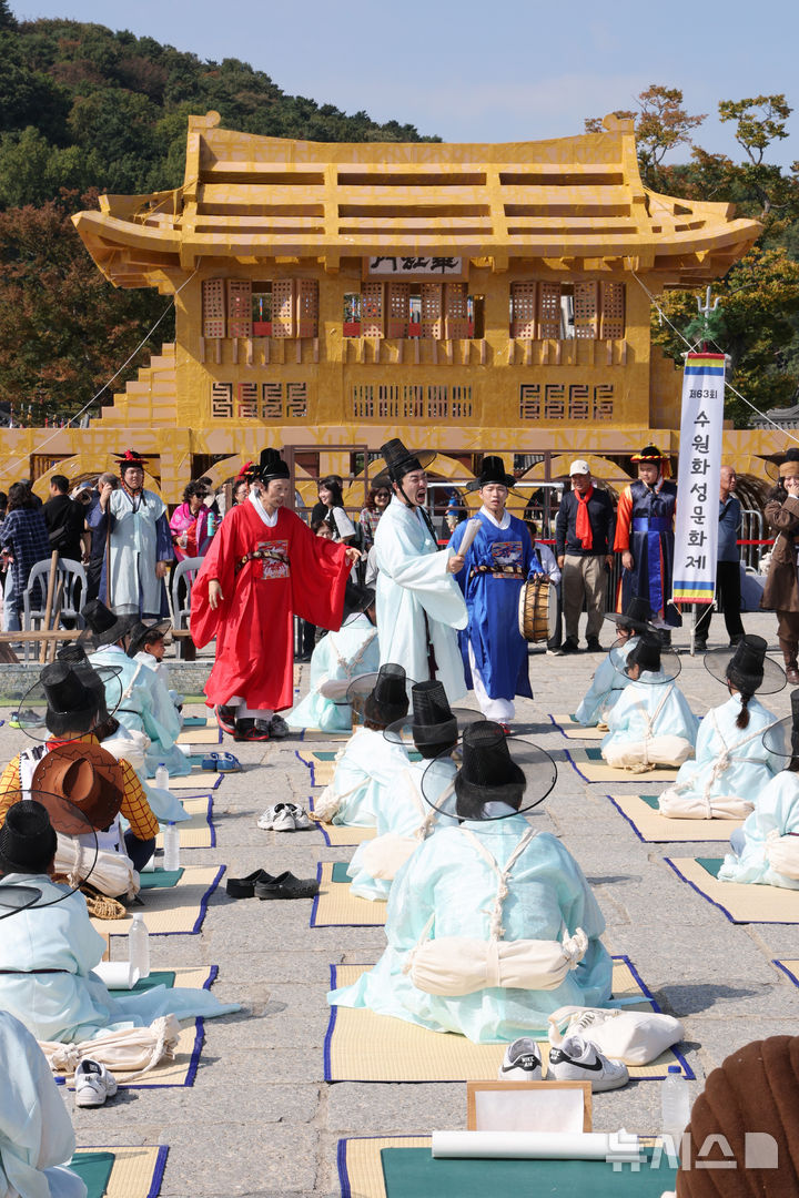 [수원=뉴시스] 김종택 기자 = 제63회 수원화성문화제가 열린 11일 경기도 수원시 화성행궁 광장에서 종이상자를 쌓아 화홍문을 실제 크기의 70%로 만든 '시민의 위대한 건축 화홍' 앞에서 조선시대 과거시험을 재현한 '별시'가 진행되고 있다. 2026.10.11. jtk@newsis.com