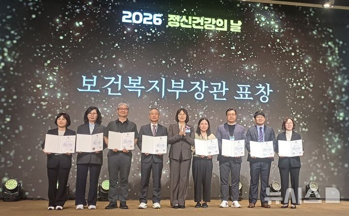 [군포=뉴시스] 경기 군포시 관계자들이 지난 8일 서울 용산구 피스앤파크 컨벤션에서 열린 '2026년 세계 정신건강의 날 기념식'에서 보건복지부 장관 표창을 수상한 뒤 기념촬영을 하고 있다.(사진=군포시 제공).2026.10.12. photo@newsis.com