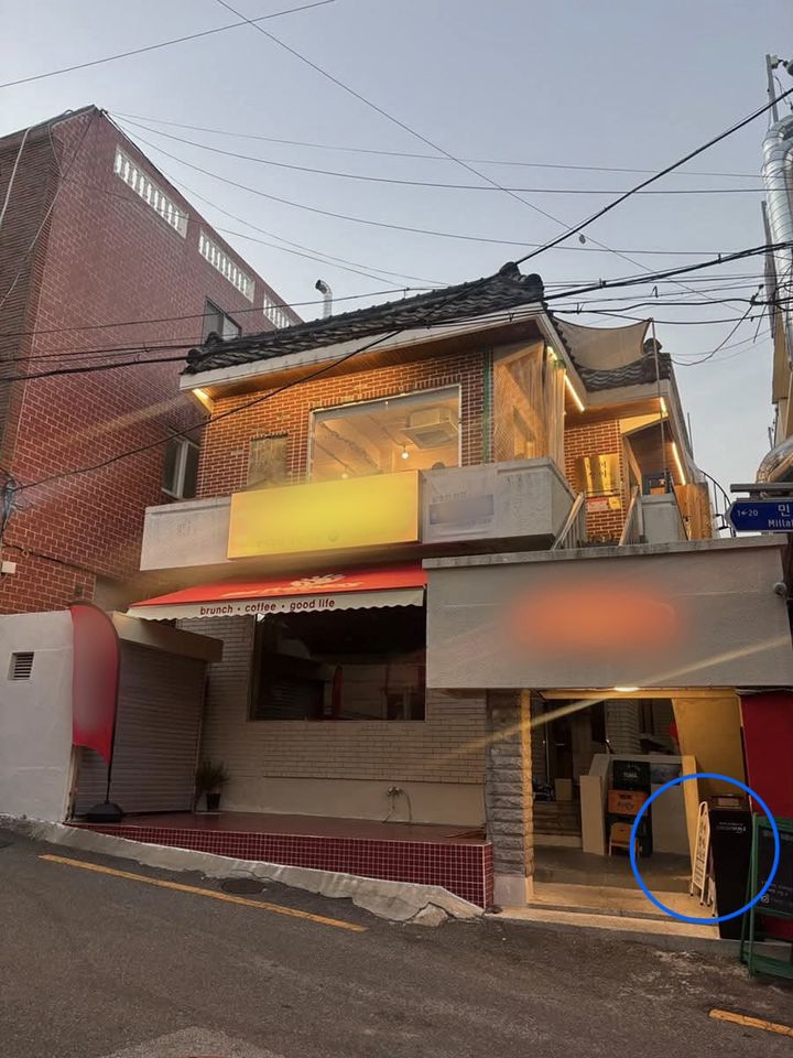 [서울=뉴시스] 갈등이 불거진 부산의 한 상가건물 외관 모습. 전층 매장이 함께 사용하는 대문 입구에 2층 매장의 입간판(파란색 동그라미)이 놓여있다. (사진출처: 스레드 캡처)2026.10.13.
