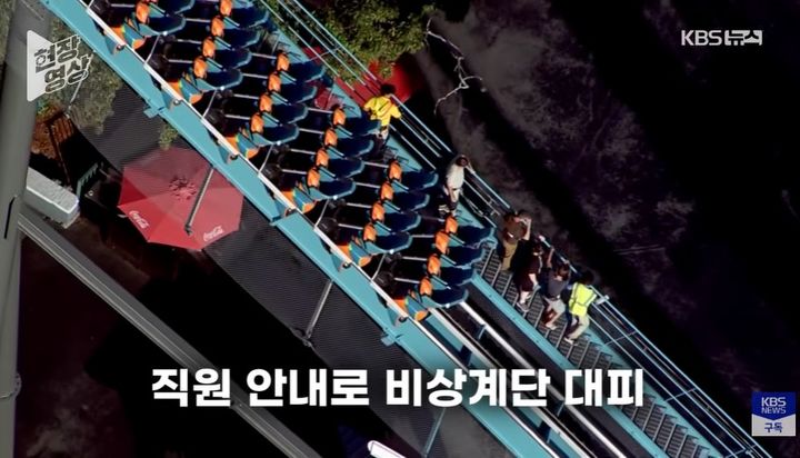 [서울=뉴시스] 미국 조지아주 놀이공원 '식스 플래그스 오버 조지아'에서 롤러코스터 '골리앗' 사고 여파로 선로에 멈춰 선 놀이기구의 탑승객들이 비상계단을 통해 대피하고 있다. (사진='KBS News' 캡처)