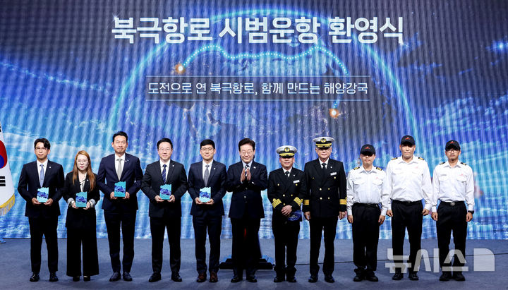 [부산=뉴시스] 조성봉 기자 = 이재명 대통령이 13일 부산에서 열린 북극항로 시범 운항 환영식에서 서명원 팬스타 아크로호 선장을 비롯한 승선원, 감사패 수상자들과 기념촬영을 하고 있다. 2026.10.13. suncho21@newsis.com