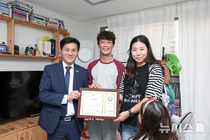 [안양=뉴시스] 윤해동 안양시의회 의장 직무대리(사진 왼쪽)가 여섯 남매 가정에 격려의 표창장을 전달하고 있다. (사진=안양시 의회 제공).2026.10.14.photo@newsis.com
