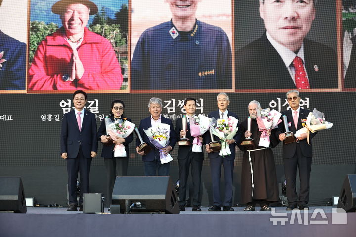 [창원=뉴시스] 박완수(맨 왼쪽) 경남도지사가 14일 오후 도청 본관 앞 특설무대에서 열린 '제43주년 경남도민의 날 기념식' 중 제2회 자랑스러운 경남인상 수상자로 선정된 6명에 대해 시상한 후 기념촬영하고 있다.(사진=경남도 제공) 2026.10.14. photo@newsis.com