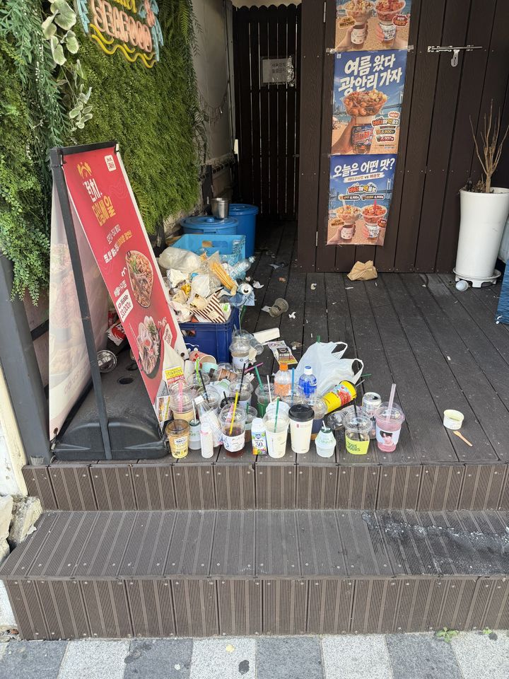 [서울=뉴시스] 부산 광안리의 한 식당 앞에 행인들이 버리고 간 음료 용기와 빈 캔 등 각종 쓰레기가 쌓여 있다. (사진출처=스레드 캡처) *재판매 및 DB 금지