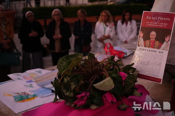 [로마=AP/뉴시스]로마의 아고스티노 제멜리 종합병원에서 입원 치료를 받고 있는 레오 14세 교황을 위해 신자들이 15일(현지시각) 고(故) 성 요한 바오로 2세 교황 동상 아래에서 기도하고 있다. 2026.10.16.
