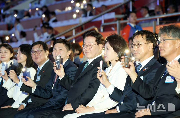 [제주=뉴시스] 김진아 기자 = 이재명 대통령과 김혜경 여사가 16일 제주월드컵경기장에서 열린 제107회 전국체육대회 개회식에서 성화봉송을 보며 휴대폰 조명을 켜고 있다. (청와대통신사진기자단) 2026.10.16. bluesoda@newsis.com