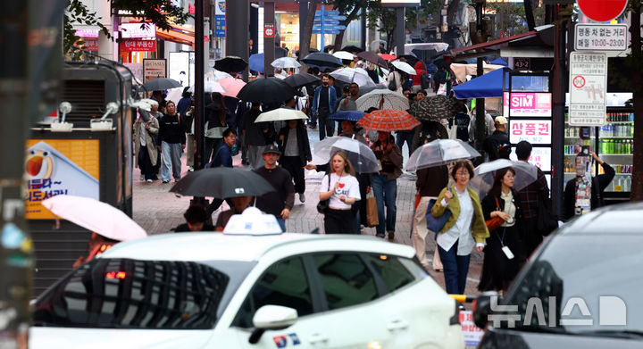 [서울=뉴시스] 전신 기자 = 월요일인 19일은 남부지방과 제주도가 대체로 흐리고 곳에 따라 비가 내리겠고, 낮 최고기온은 평년 수준을 회복하겠다. 사진은 비가 내린 18일 서울 명동거리에서 시민들과 관광객들이 우산을 쓰고 이동하는 모습. 2026.10.18. photo1006@newsis.com