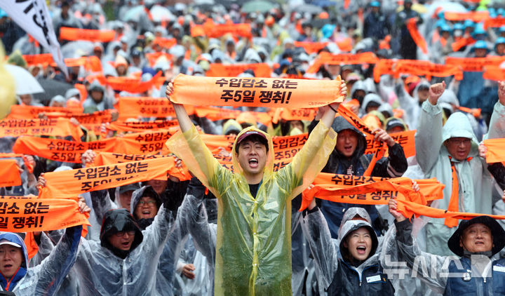 [서울=뉴시스] 전신 기자 = 18일 서울 중구 숭례문 인근에서 열린 전국택배노동자대회에서 참석자들이 구호를 외치며 '수입 감소 없는 주5일 쟁취' 문구가 적힌 손푯말을 들어보이고 있다. 2026.10.18. photo1006@newsis.com