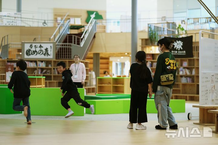[오쿠마=AP/뉴시스] 19일 아사히신문 등 현지 언론에 따르면 일본 정부가 디지털 교과서를 도입한 뒤에도 종이 교과서와 함께 쓰도록 할 방침이다. 사진은 2026년 2월10일 일본 동북부 오쿠마의 마나비야 유메노모리 학교·유치원에서 학생과 실습생(오른쪽)이 도서관 공간에서 장난치는 다른 학생들을 바라보는 모습. 2026.10.19.