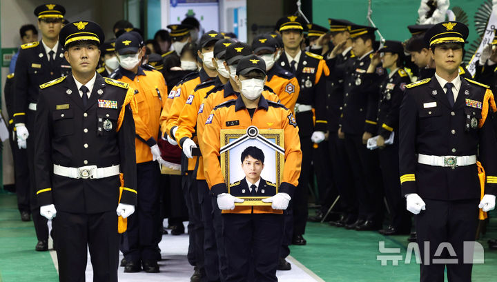 [부천=뉴시스] 전진환 기자 = 부천 공장 화재 진압 과정에서 순직한 김진석 소방위의 영결식이 엄수된 19일 경기도 부천시 원미구 부천체육관으로 고인의 영정이 들어오고 있다. (공동취재) 2026.10.19. photo@newsis.com