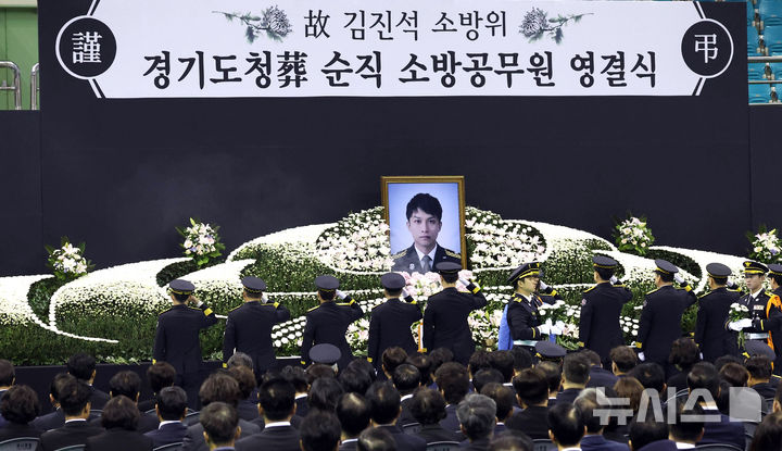[부천=뉴시스] 전진환 기자 = 부천 공장 화재 진압 과정에서 순직한 김진석 소방위의 영결식이 엄수된 19일 경기도 부천시 원미구 부천체육관에서 동료 소방관들이 헌화 후 경례하고 있다. (공동취재) 2026.10.19. photo@newsis.com