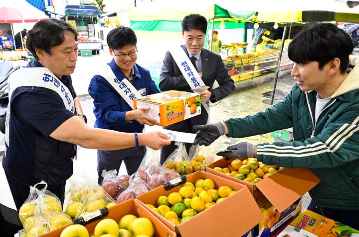 [울산=뉴시스] 현대자동차 노사 관계자들이 20일 울산 북구 염포시장에서 전통시장 장보기 행사를 열고 과일을 구입하고 있다. (사진=현대자동차 제공) 2026.10.20. photo@newsis.com *재판매 및 DB 금지