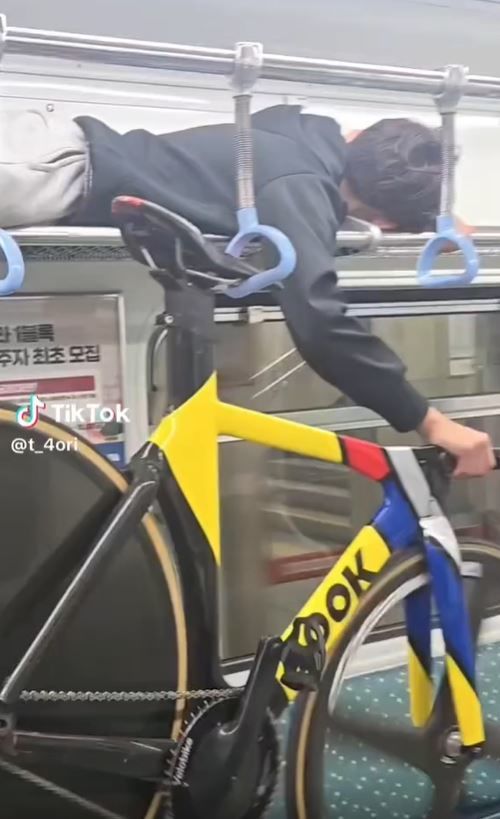 [서울=뉴시스] 부산 지하철에서 한 남학생이 좌석 위 짐칸에 올라가 한 손으로 자전거를 들어 올리고 있다. (사진출처=소셜미디어 캡처) *재판매 및 DB 금지