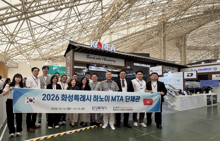 [화성=뉴시스] '베트남 하노이 기계전시회'에 참가한 경기 화성시 기업 관계자들이 화성시 단체관 앞에서 기념촬영을 하고 있다. (사진=화성시 제공) 2026.10.21. photo@newsis.com&nbsp;&nbsp; *재판매 및 DB 금지