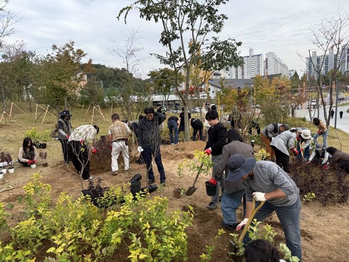 [수원=뉴시스] 지난 20일 경기 수원시 영통구 영흥숲공원 에코브릿지 상부에서 열린 탄소저감숲 조성 기념 식재 행사에서 참가자들이 나무를 심고 있다.. (사진=수원시 제공) 2026.10.21. photo@newsis.com *재판매 및 DB 금지