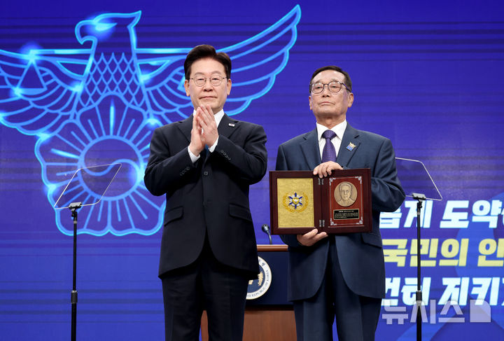 [서울=뉴시스] 조성봉 기자 = 이재명 대통령이 21일 서울 서대문구 경찰청에서 열린 제81주년 경찰의 날 기념식에서 경사 심연수의 아들 심상순 씨에게 경찰영웅 인증패를 전달 후 기념촬영을 하고 있다. 2026.10.21. suncho21@newsis.com