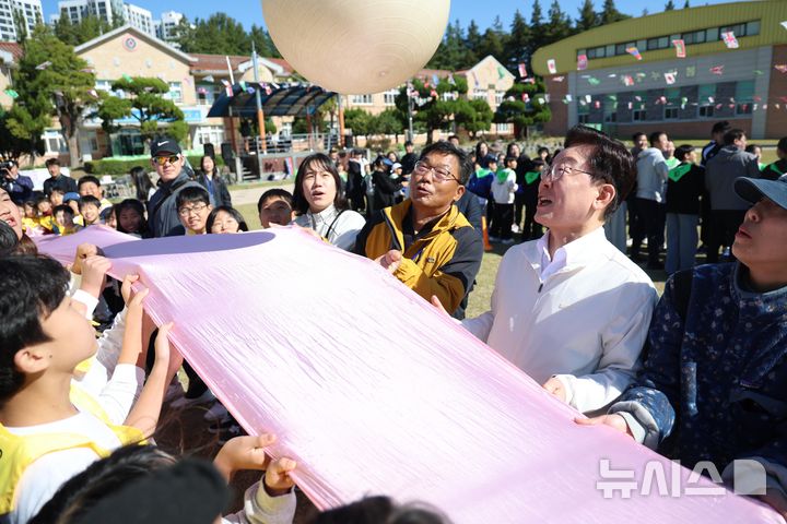 [익산=뉴시스] 김진아 기자 = 이재명 대통령이 22일 전북 익산 왕궁초등학교에서 열린 가을 행복학교 체육한마당에서 학생들과 '짐볼 이동하기'를 하고 있다. 2026.10.22. bluesoda@newsis.com