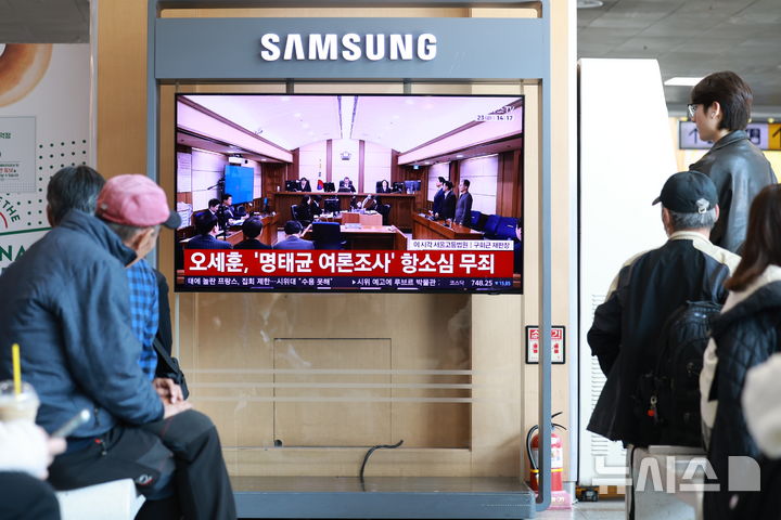 [서울=뉴시스] 이영환 기자 = 23일 오후 서울 용산구 서울역에서 시민들이 오세훈 서울시장의 정치자금법 위반 혐의 항소심 선고공판을 시청하고 있다. 오 시장은 항소심에서 무죄를 선고 받았다. 2026.10.23. 20hwan@newsis.com