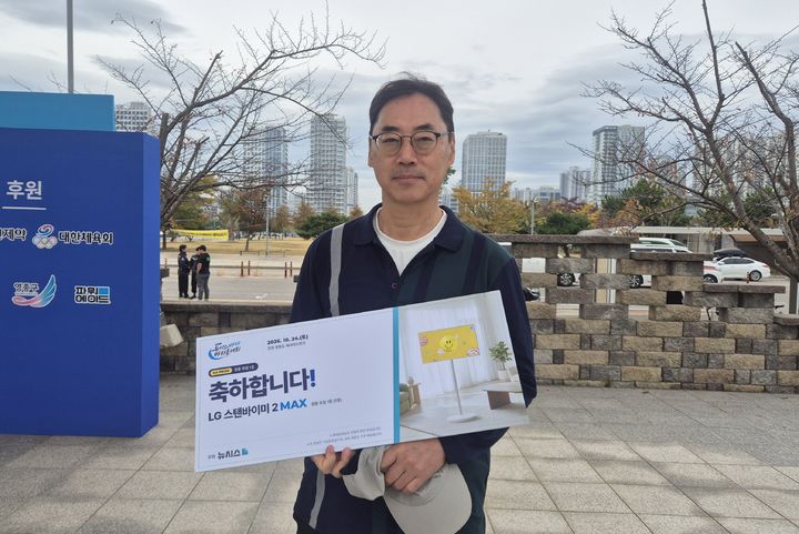 [인천=뉴시스] 문채현 기자 = 박재일씨가 24일 인천광역시 영종구 영종도 씨사이드파크 일대(하늘구름광장)에서 열린 2026 뉴시스 바다마라톤대회에서 1등 경품에 당첨돼 기념 사진을 찍고 있다. 2026.10.24. dal@newsis.com *재판매 및 DB 금지