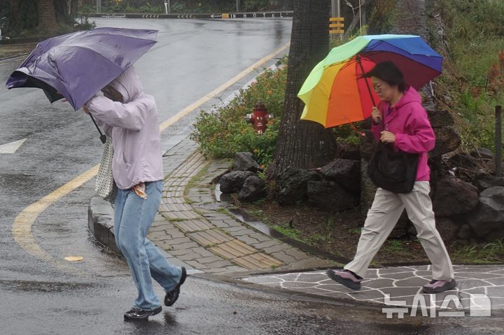 [제주=뉴시스] 양영전 기자 = 제주에 호우·강풍 특보가 발효된 가운데 25일 오전 제주 용담해안도로를 찾은 관광객들이 우산을 쓰고 걷고 있다. 2026.10.25. 0jeoni@newsis.com 